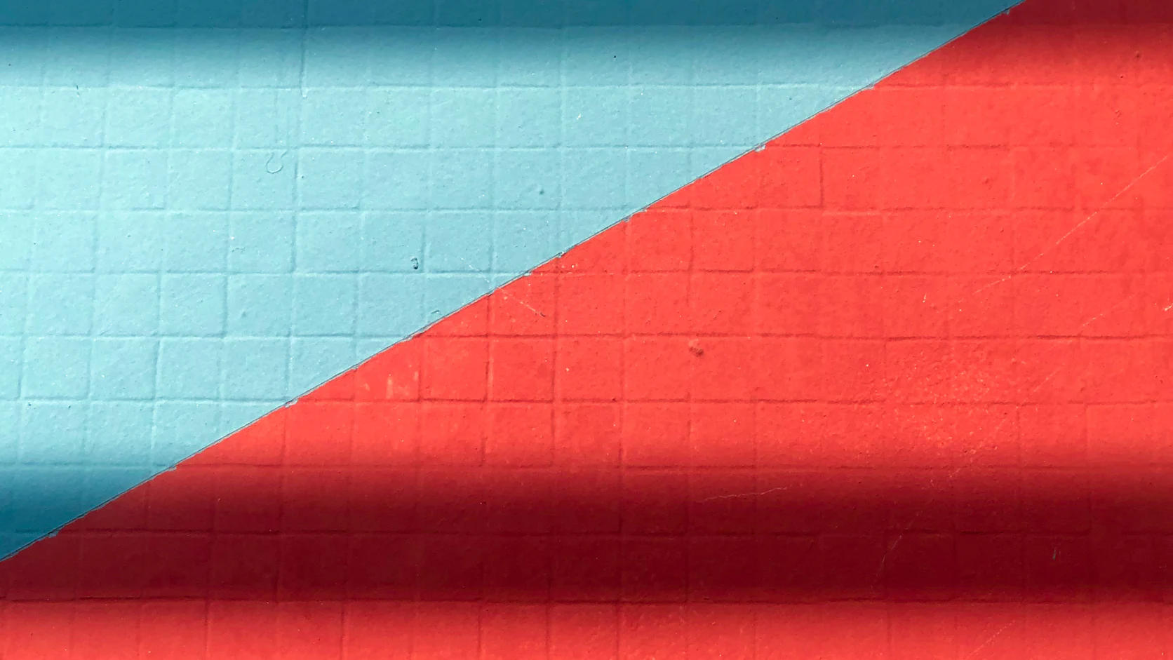 A red wall and a pale blue wall meeting on a sharp diagonal